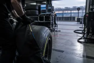 Formula 1 pit garage preparations unfolding between qualifying and the race in soft morning light.