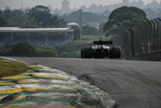 Formula 1 car accelerating uphill out of Interlagos’s Junção on a humid morning.